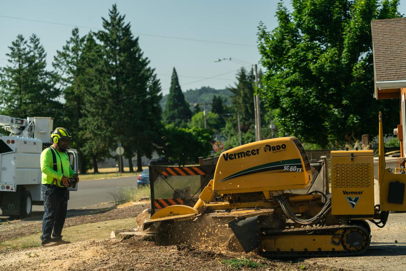 Oregon Woodsmen crew grinding a stump in a front yard